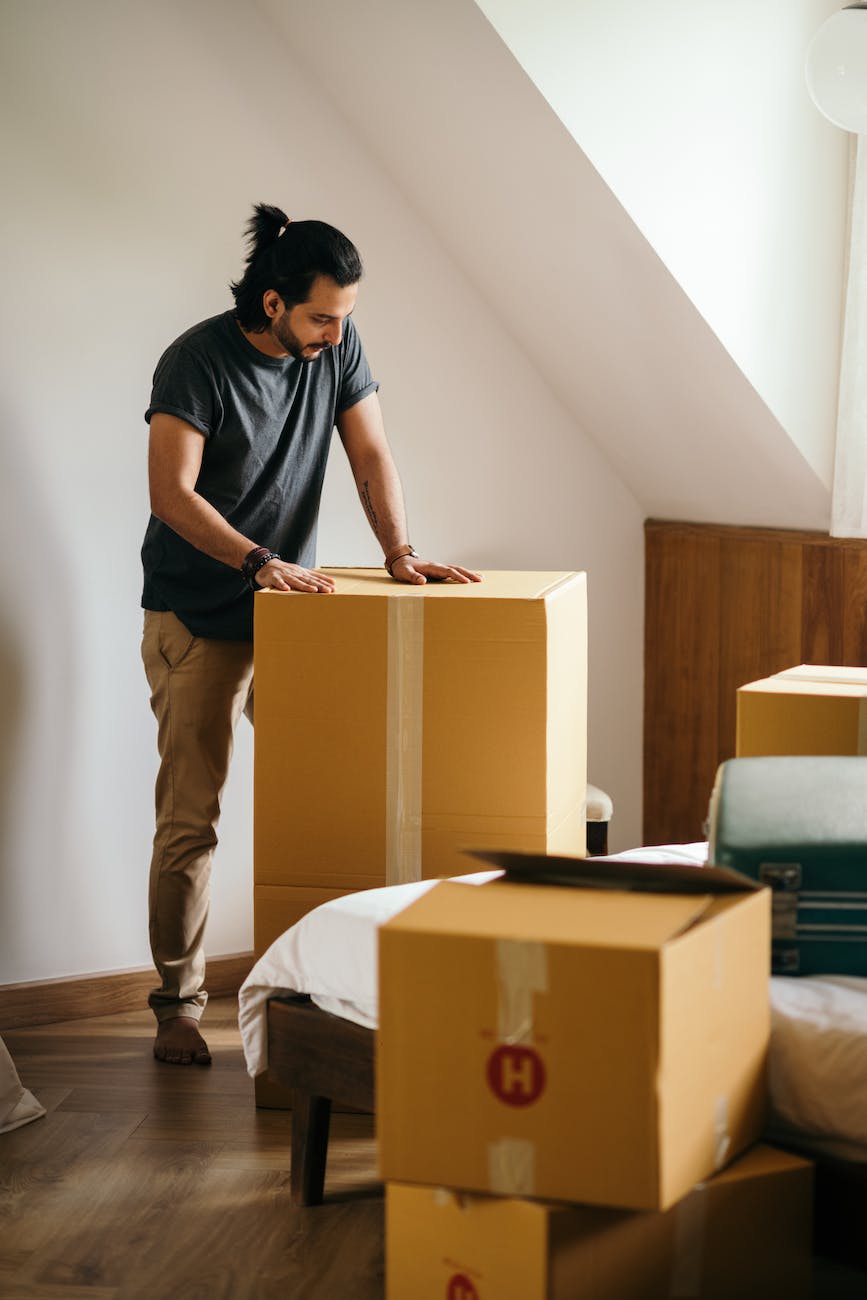 young man packing cardboard boxes at home