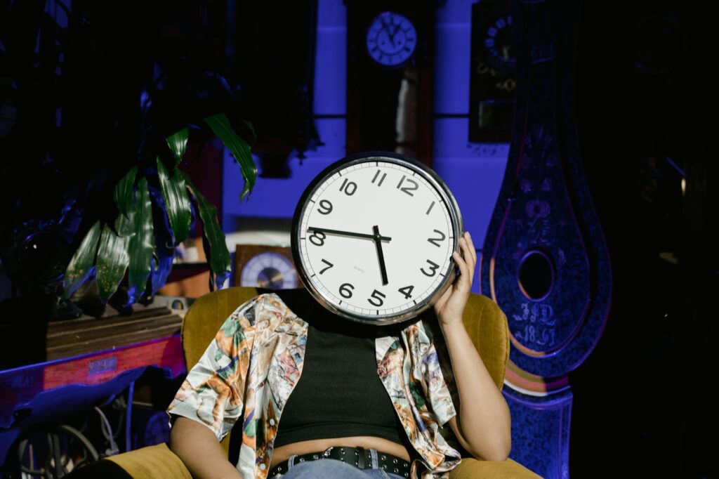 a person sitting on the yellow armchair with a clock on her face